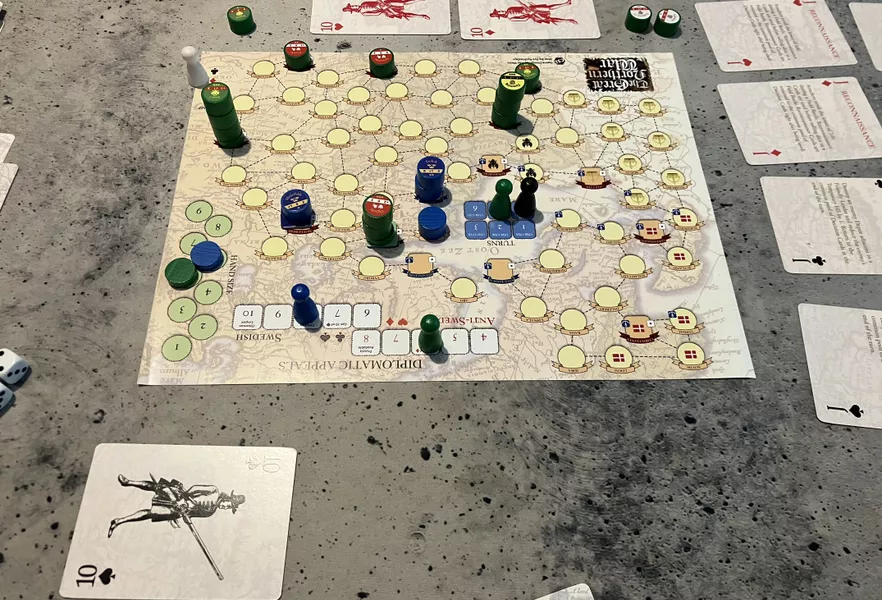 The Great Northern War in play. Board with wooden army pieces, diplomacy track, and playing cards on a table.